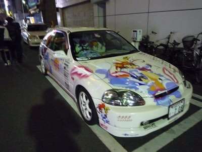 Japão: Tokyo de novo – Minoru e Juba – Primeiro Dia Carro branco decorado com personagens de anime em uma rua de Tokyo