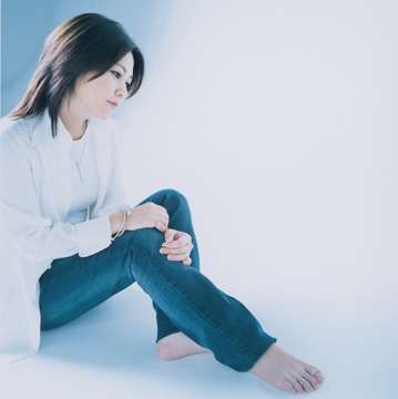 Rimi Natsukawa sentada, usando camisa branca e calça jeans