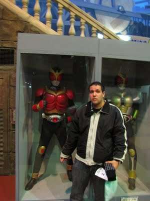 Giuliano Peccilli diante de figuras de Kamen Rider